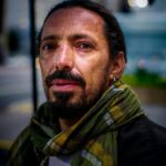 Man with a beard and scarf on the streets of São Paulo, Brazil, at dusk.