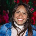 Portrait of a joyful woman smiling warmly with a vibrant floral backdrop.